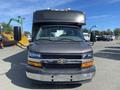 A gray 2017 Chevrolet Express bus with visible headlights and mirrors facing forward