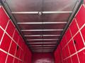 Interior view of a red truck trailer with metal beams and ceiling lights visible