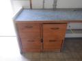 A wooden countertop with a gray surface featuring four cabinet doors below with handles