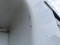 A close-up of the side of a white 2020 Chevrolet Express showing minor scratches and scuff marks on the surface