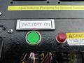 A control panel featuring a green button labeled Battery On a red light and a caution sign