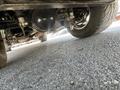 The underside of a 1962 Ford F-100 showcasing its exhaust system and rear axle with a tire in focus on the right
