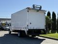 A white 2013 Ford Econoline box truck facing away with a rack on top and signage on the rear door
