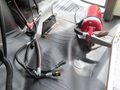 A red fire extinguisher mounted on a black floor with exposed wiring and connectors from a 2020 Chevrolet Express