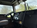 Interior view of a 1996 Kenworth T800 truck featuring a black dashboard with gauges and controls a steering wheel and a gear shift lever
