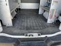 The interior cargo area of a 2014 Chevrolet Express van with a rubber floor mat and metal shelving on both sides