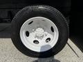 A close-up view of a tire mounted on a white wheel with six lug nuts and a smooth black rubber surface