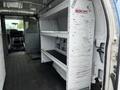 Interior of a 2009 Ford Econoline van featuring metal shelving units along one side and a driver's seat visible in the front
