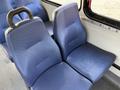 A pair of blue fabric bus seats with a textured surface and a black handle on the side