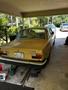 A yellow 1978 Volvo 244 parked in a garage with its rear view facing the viewer showing a distinctive boxy shape and tail lights
