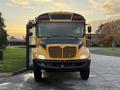 A yellow 2014 International 4300 school bus facing forward with large headlights and a black front grille