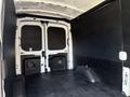 A 2022 Ford Transit van with its rear doors open revealing a spacious empty cargo area featuring black walls and a flat floor