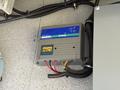 A charging device with a blue and gray casing labeled Guest 10 Amp mounted on a surface with wires connected to it