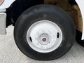 Close-up of a white wheel rim with a central hub and lug nuts mounted on a black tire of a 2006 Hino 268 truck