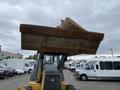 A 2012 John Deere 310SJ backhoe loader with a raised bucket in the foreground