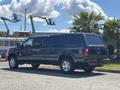 A blue 2014 Ford F-250 Super Duty pickup truck with a cap on the bed and large tires parked sideways
