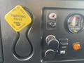 A close-up view of the dashboard controls in a 2016 International 7400 showing a yellow parking brake lever and various gauges and buttons including a filter minder and engine intake