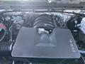 The engine bay of a 2016 GMC Sierra 1500 showing the engine cover with 5W30L written on it along with various engine components and hoses visible in the foreground