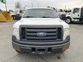 A 2010 Ford F-150 with a white exterior and a black grille centered with the Ford logo showing signs of rust on the front bumper