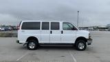 A white 2017 Chevrolet Express Quigley 4x4 van with multiple windows and chrome wheels parked in an open lot