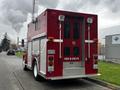 A red 1995 Freightliner FL70 fire rescue truck with a compartmented body and visible emergency lights on the rear