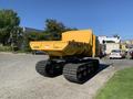 A yellow 2022 TerraMac tracked dump with a large flat bed and wide tracks designed for off-road transport