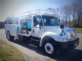 A white 2011 International DuraStar 4300 truck with a flatbed and mounted equipment in the back