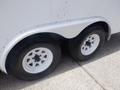 A close-up view of two black tires mounted on a white trailer with a silver fender and visible wheel rims