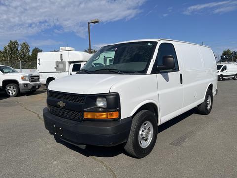 A white 2013 Chevrolet Express van facing forward with a black grille and round headlights parked on a paved surface