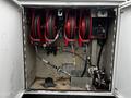 The image shows the interior of a storage compartment featuring three red hose reels along with a control panel and plumbing equipment