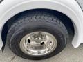 A close-up view of the front tire of a 2014 Chevrolet Express showcasing its tread pattern and shiny chrome rim