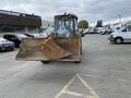 A 2012 John Deere 310SJ backhoe loader with a rusty front bucket facing forward parked in a lot
