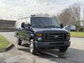 A blue 2011 Ford Econoline van parked with a boxy front design and chrome accents on the grille and wheels