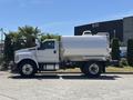 A 2019 Ford F-750 truck with a silver tank attached to its bed is parked on a street, showcasing its large wheels and sturdy build