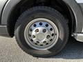 A close-up of a silver wheel with eight rounded lug nut holes and a black tire on a 2023 Ford Transit