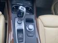 The image shows the center console of a 2009 BMW X5 featuring a gear shift lever and control knobs with a wood finish