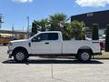 A white 2020 Ford F-350 SD pickup truck is parked with its side profile visible showcasing its 4x4 emblem and chrome wheels