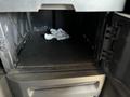 An open compartment in a 2022 Freightliner Cascadia revealing empty space and crumpled paper inside