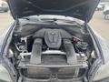 The engine compartment of a 2009 BMW X5 featuring a V8 engine with a black cover and visible components such as hoses and filters