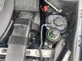 Engine compartment of a 2009 BMW X5 showing various components including hoses a coolant reservoir and a black air intake system
