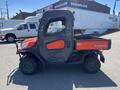 A 2014 Kubota X1100C utility vehicle featuring a bright orange and gray cab with a flatbed marked with the Kubota logo and rugged tires designed for off-road use