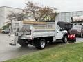 A 2021 Ford F600 truck with a silver dump bed and a salt spreader attached to the rear
