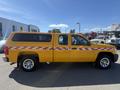 A 2013 Chevrolet Silverado 1500 pickup truck with a yellow exterior and a checkerboard design along the sides parked on a lot