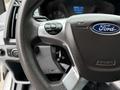 Close-up of a steering wheel in a 2018 Ford Transit featuring controls for audio and cruise settings with the Ford logo prominent on the center hub