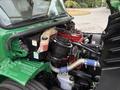 The engine compartment of a 2015 Freightliner M2 106 featuring a red engine with black components and visible hoses and fluid reservoirs in green casing