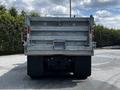 Rear view of a 2010 Freightliner M2 106 dump truck with a silver metal bed and safety chains attached