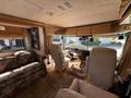 Interior of a 2000 Ford Motorhome featuring a floral sofa and two captain chairs with a steering wheel and dashboard visible in the front area