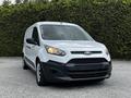 White 2014 Ford Transit Connect van with a black grille and headlights on, parked on a flat surface