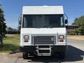 A white 2019 Freightliner MT45 delivery truck with a flat front and large windows is parked facing forward with a prominent grille and headlights visible