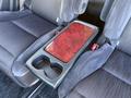 A 2009 Toyota Vellfire center console with a glossy wood panel and a cup holder between two dark fabric seats
